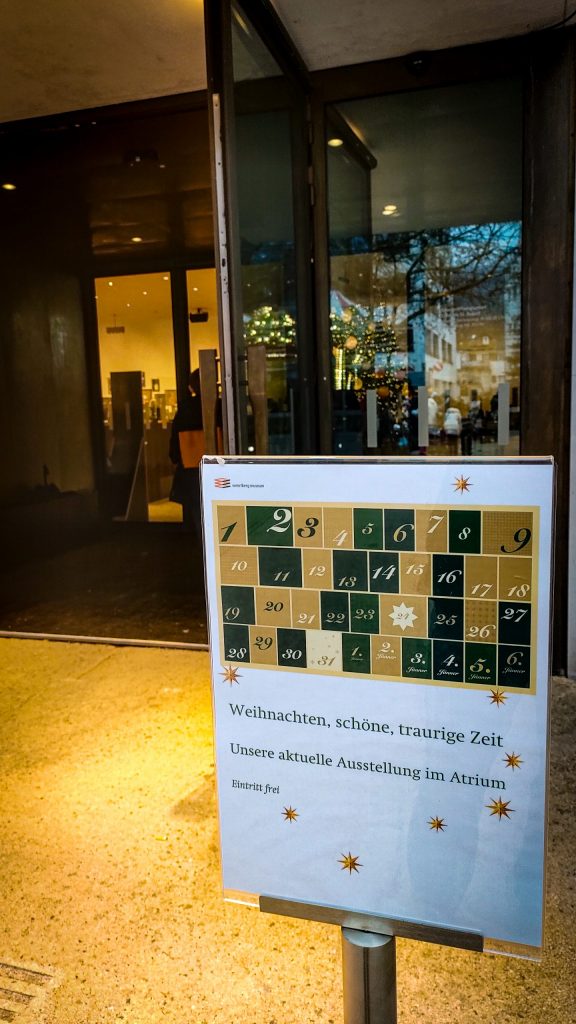 Eine Hinweistafel, die Besucher zur Ausstellung "Weihnachten, schöne, traurige Zeit" einlädt